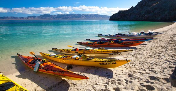 Kayaks beached on the shore by the turquoise waters of Baja California, Mexico.