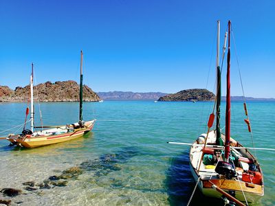 Two sailboats anchored near the shore in the bright aqua waters of Baja California, Mexico.  