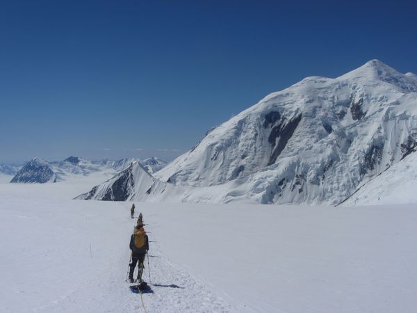 Members of the Expedition Denali team pull gear sleds across a snowfield. 