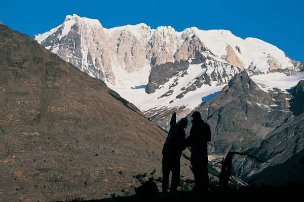 Two silhouetted students in the mountains of Patagonia practice route-finding while looking out at craggy snow-crusted peaks.