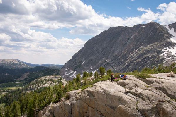 Participants gathered on a rock outcrop ringed with pines in the mountains.
