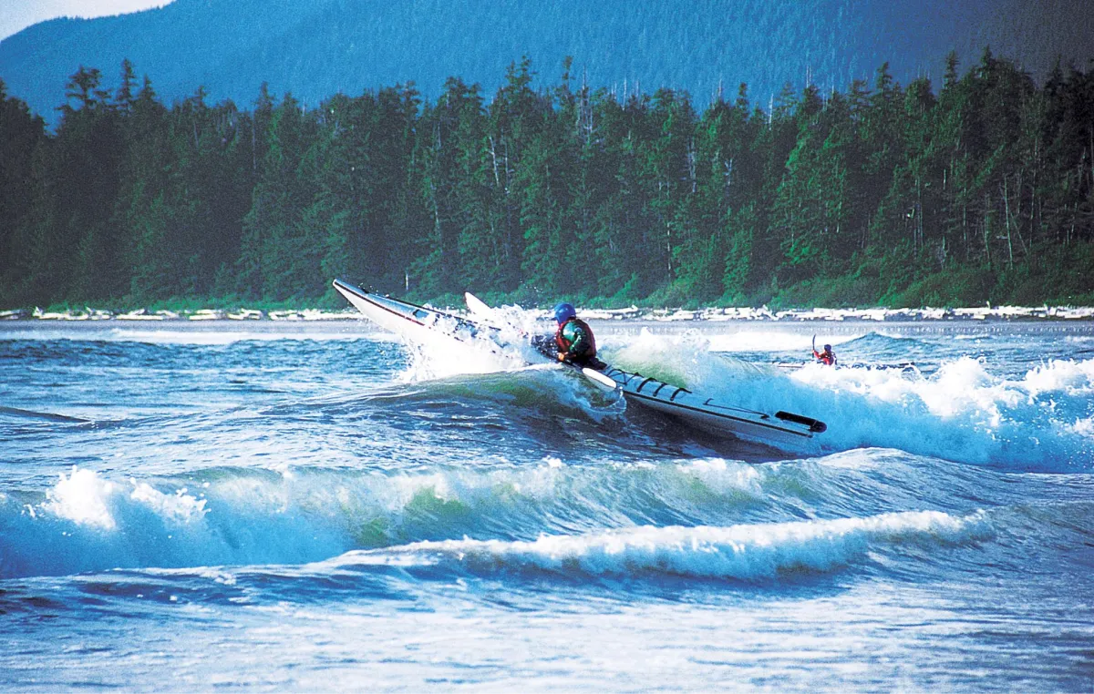 doug_demarest_pnw A course participant crests a large wave with a sea kayak in the waters of coastal British Columbia.