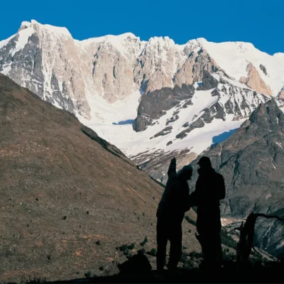 Two silhouetted students in the mountains of Patagonia practice route-finding while looking out at craggy snow-crusted peaks.