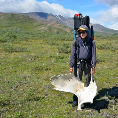 A student holds up her discovery (a moose antler) while out backpacking in the Wrangell Mountains.