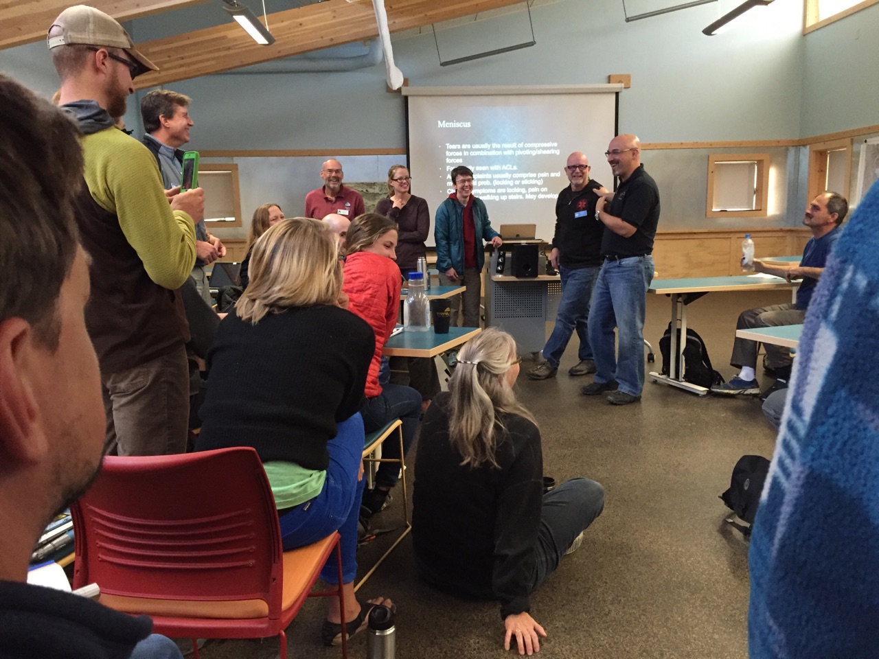 class-wilderness-medicine-nols-staff-meeting Participants stand and sit in a classroom during a workshop