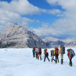 Group of students walking across a flat landscape with backpacks, snow gear and ice picks
