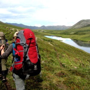 two women backpacking along a small pond through the backcountry