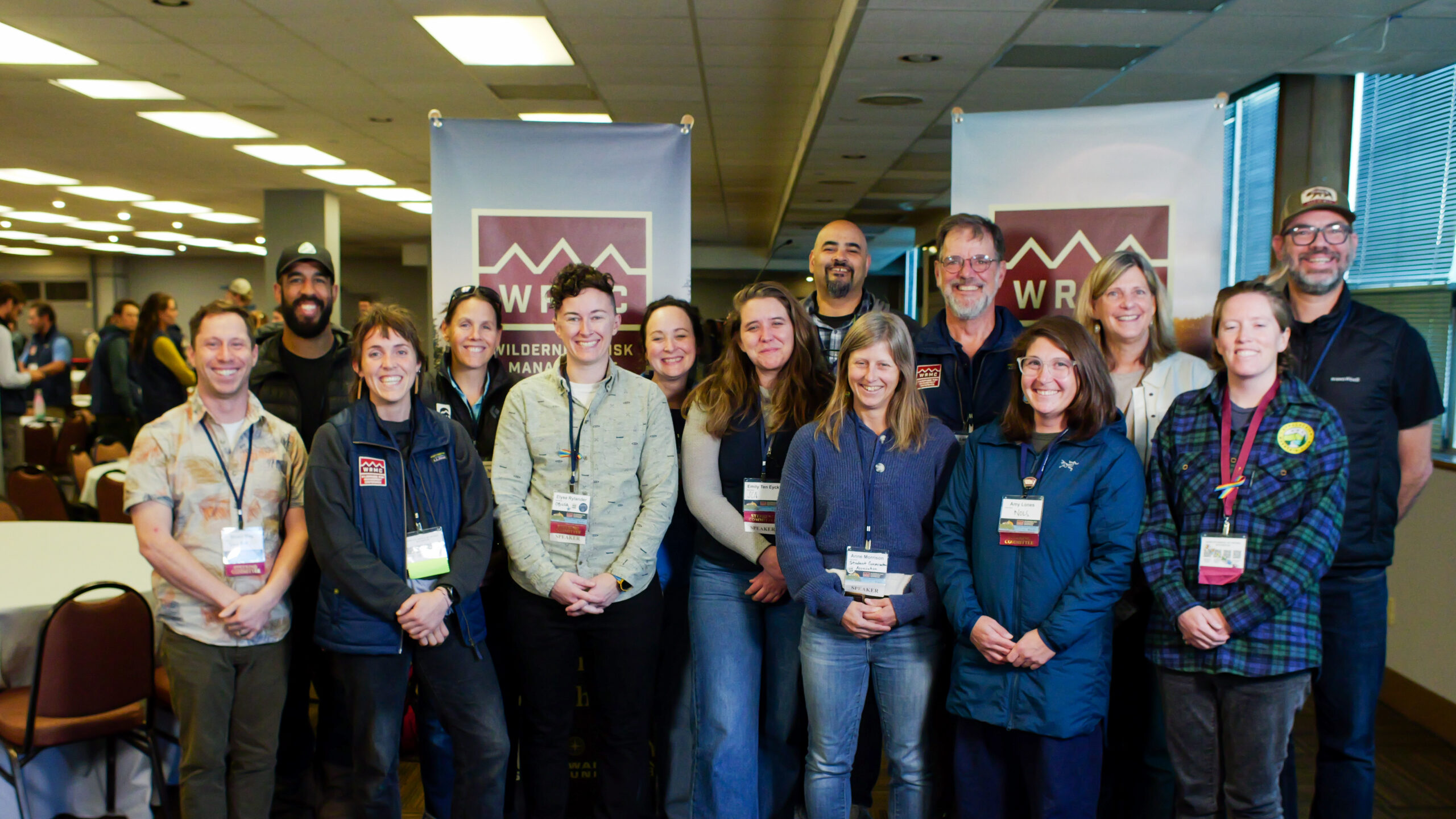 A group of 14 people all wearing lanyards pose in front of signs reading WRMC.