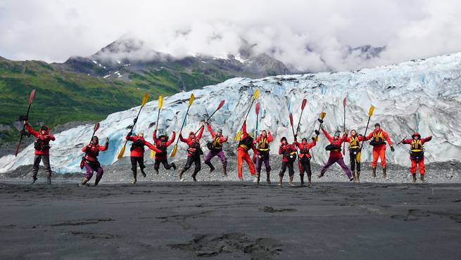 devin-duffy-ak-9.jpg__655x5000_q70_subject_location-3237,1715_subsampling-2 A course jumps together with their sea kayaking paddles on a beach in Alaska.