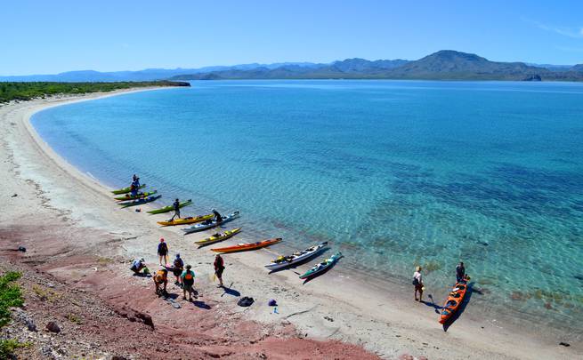 Students loading up their sea kayaks on shore next to the stunning aqua waters of the Sea of Cortez in Baja California, Mexico.