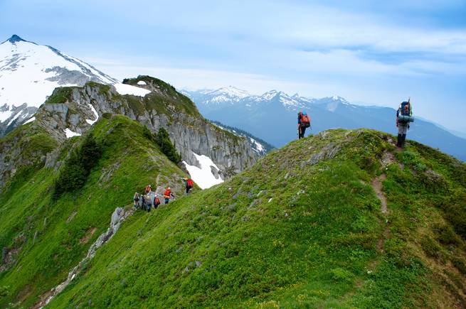 nick-cross-dsc04470.jpg__655x5000_q70_subject_location-2035,1380_subsampling-2 Students backpacking on scenic green hills amidst the snowy peaks of the North Cascades.