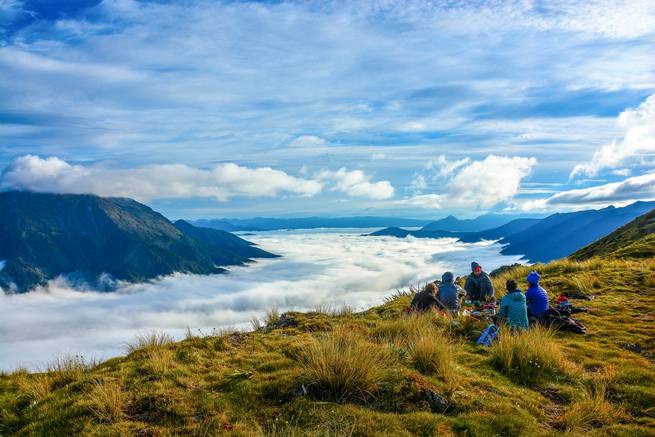 Course participants sit on a grassy ridge above the clouds in Kahurangi National Park.
