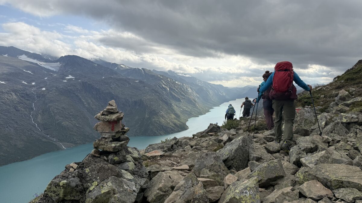 River running between mountains, group of four on right and large cairn on right.