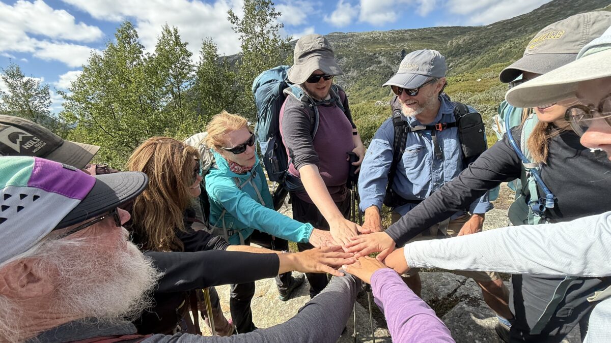 Norway group of at least nine people gather and touch palms for a group high-5.