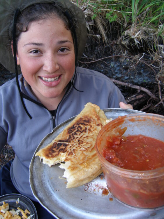 Young woman showing plate with bread and picante sauce on it.