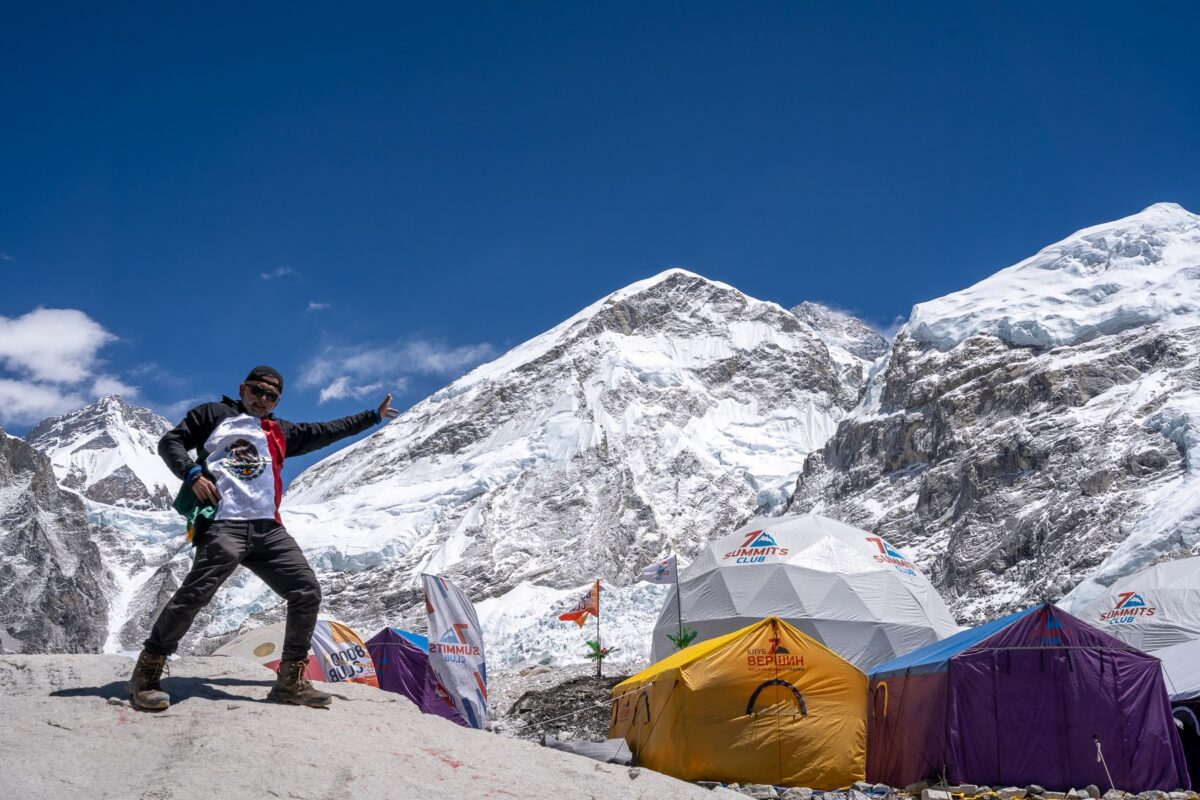 Team member, left, goof around, posing as though he's touching a distant peak. Camp tents are visable on the right.