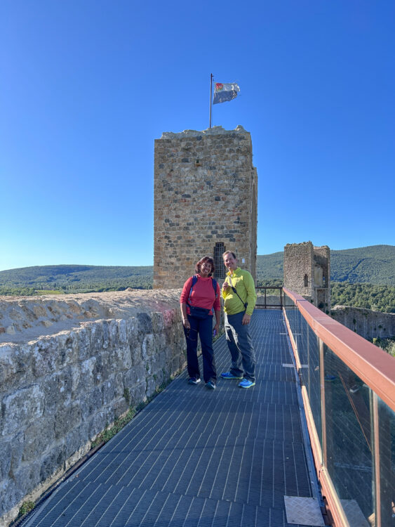 Hikers smile in front of a stone lookout tower.