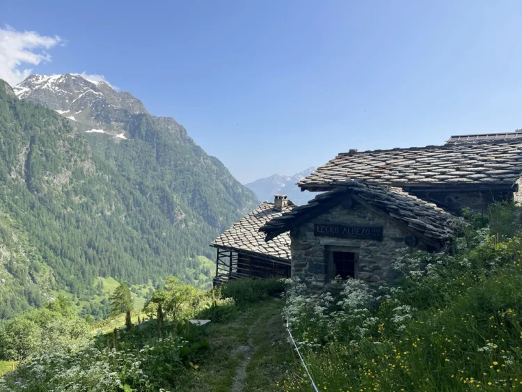 Mountain hut with mountains and sunshine behind.