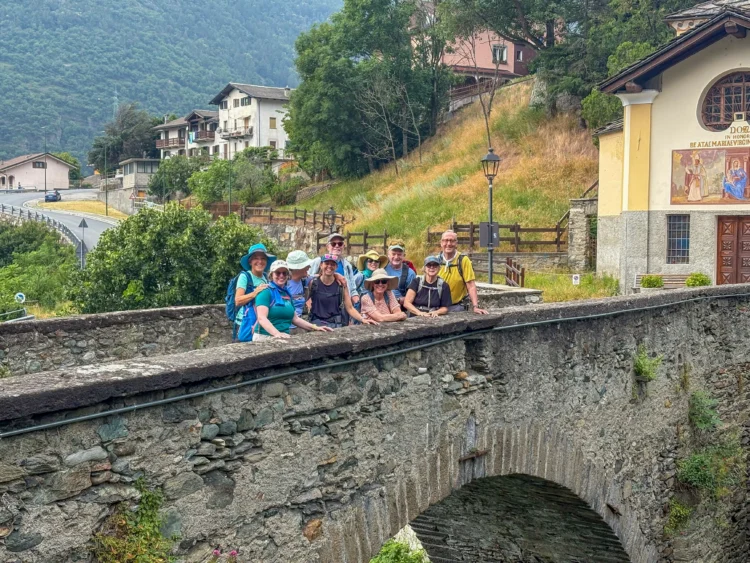 Hikers pose on a stone bridge.