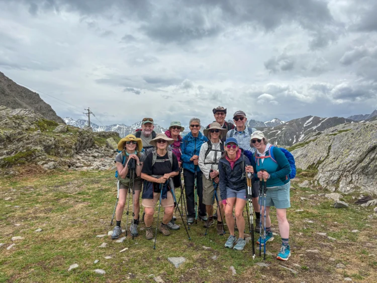 A group of hikers poses with mountains in the background.
