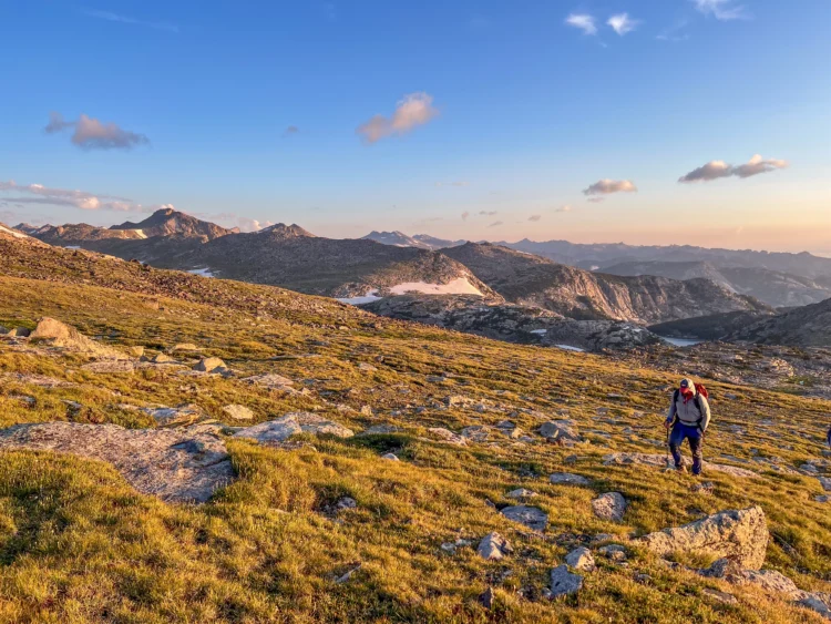 A hiker walks across the tundra at sunrise.