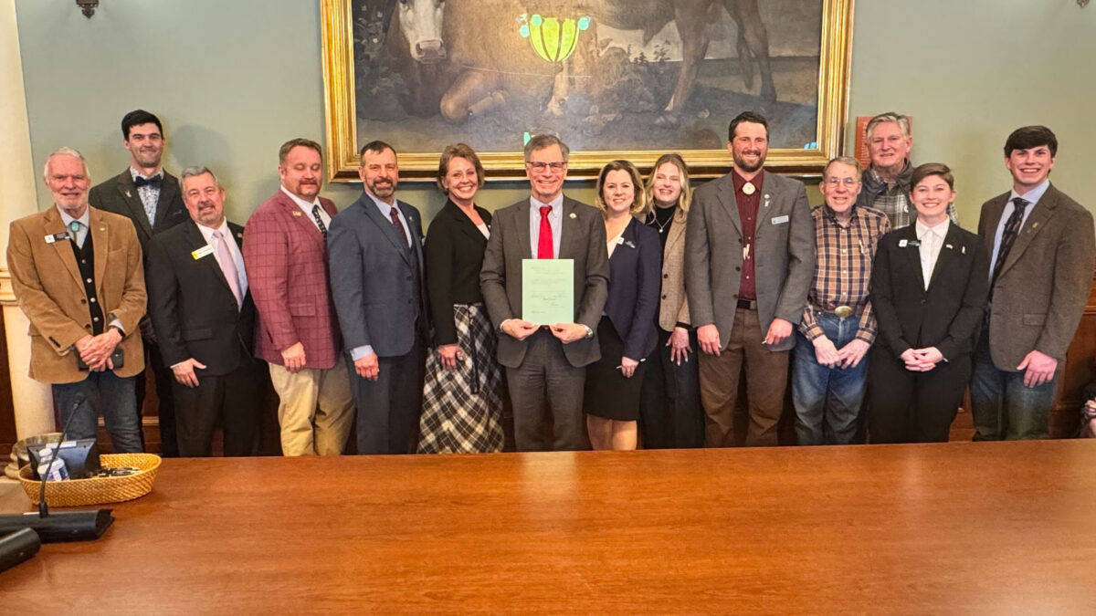 a group of people in formal attire stand holding a new resolution.