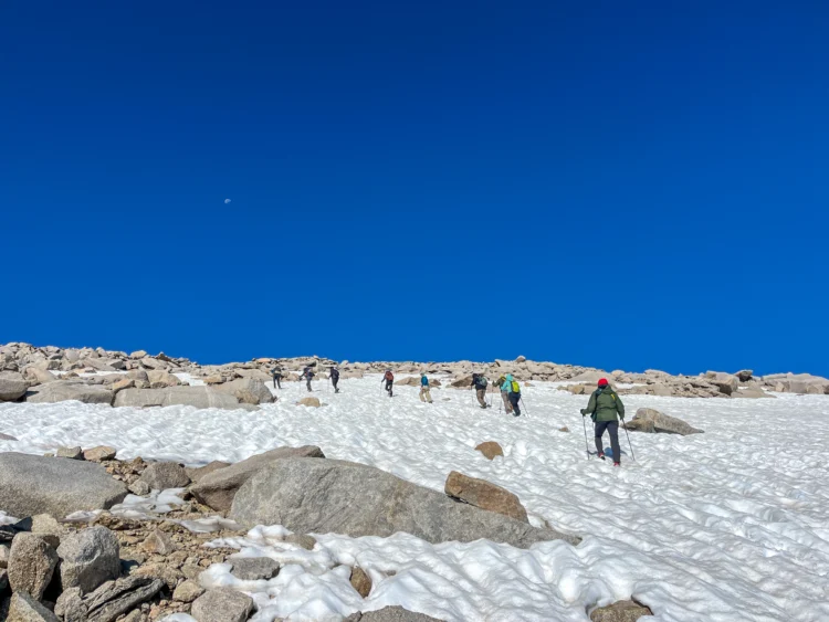 Hikers walk across the snow.