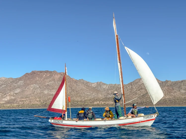 Sailors navigate the Sea of Cortez with mountains behind them