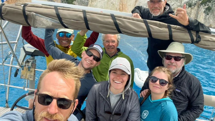 Sailors smile with the sail behind them