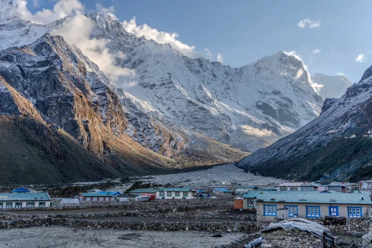 A village stands at the base of the snow capped mountains