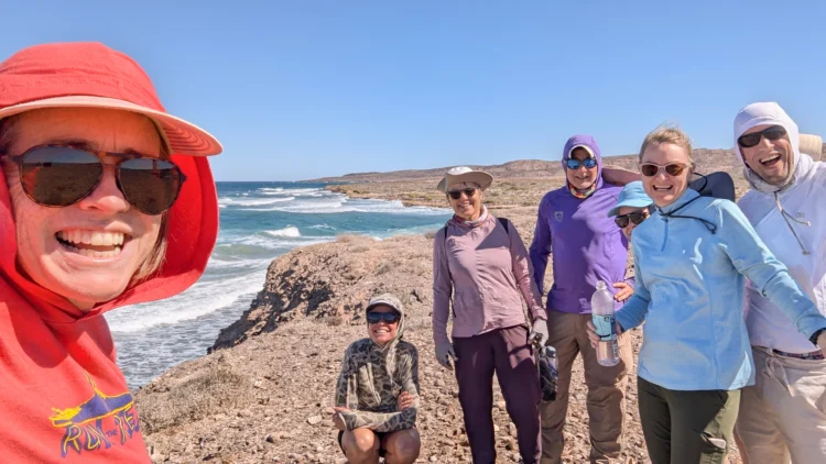 Sailors pose on the beach with blue water and skies behind