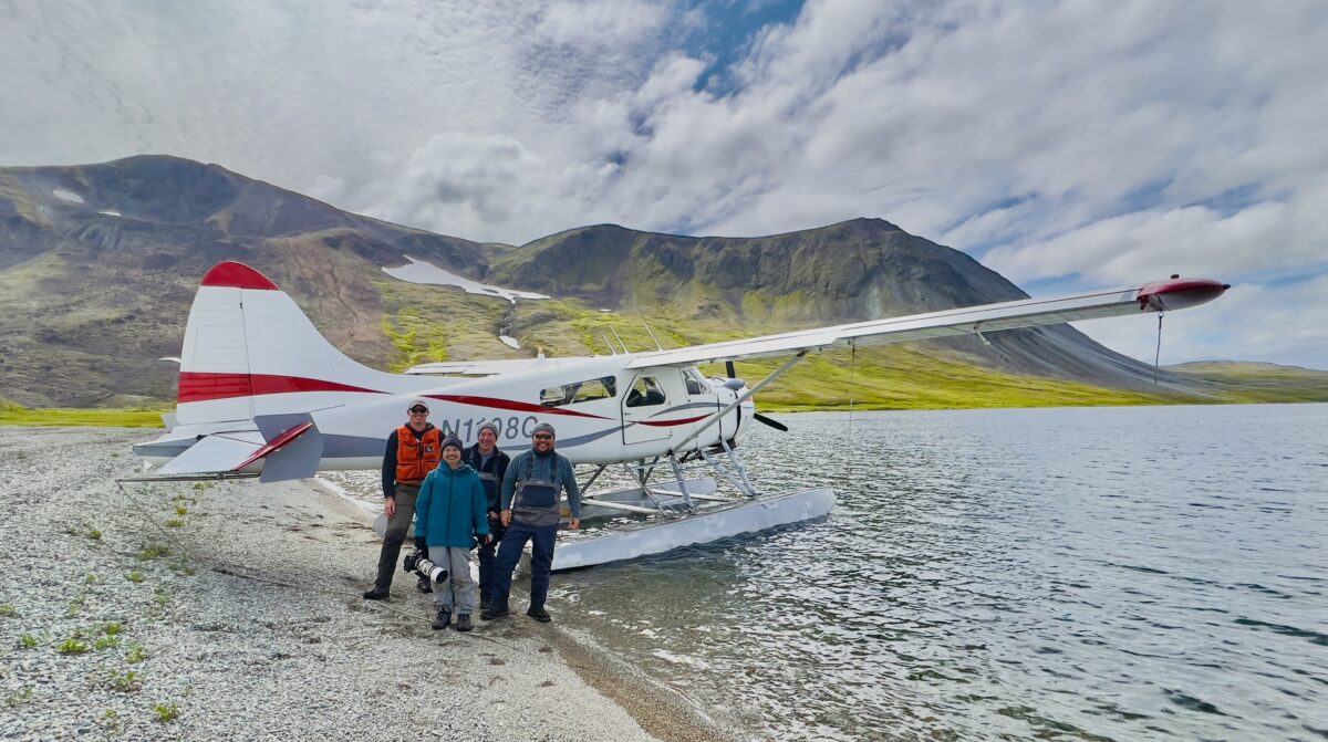 Asa and others stand on a beach, just feet from Asa's plane.