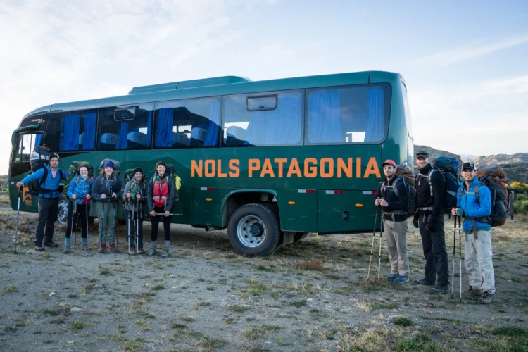 a large group of people stand in front of a bus that says NOLS Patagonia