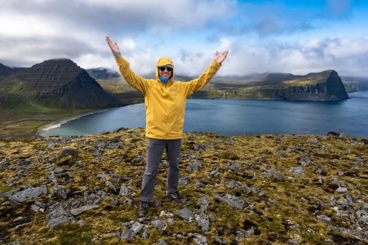 Hiker smiles with arms in the air in Iceland