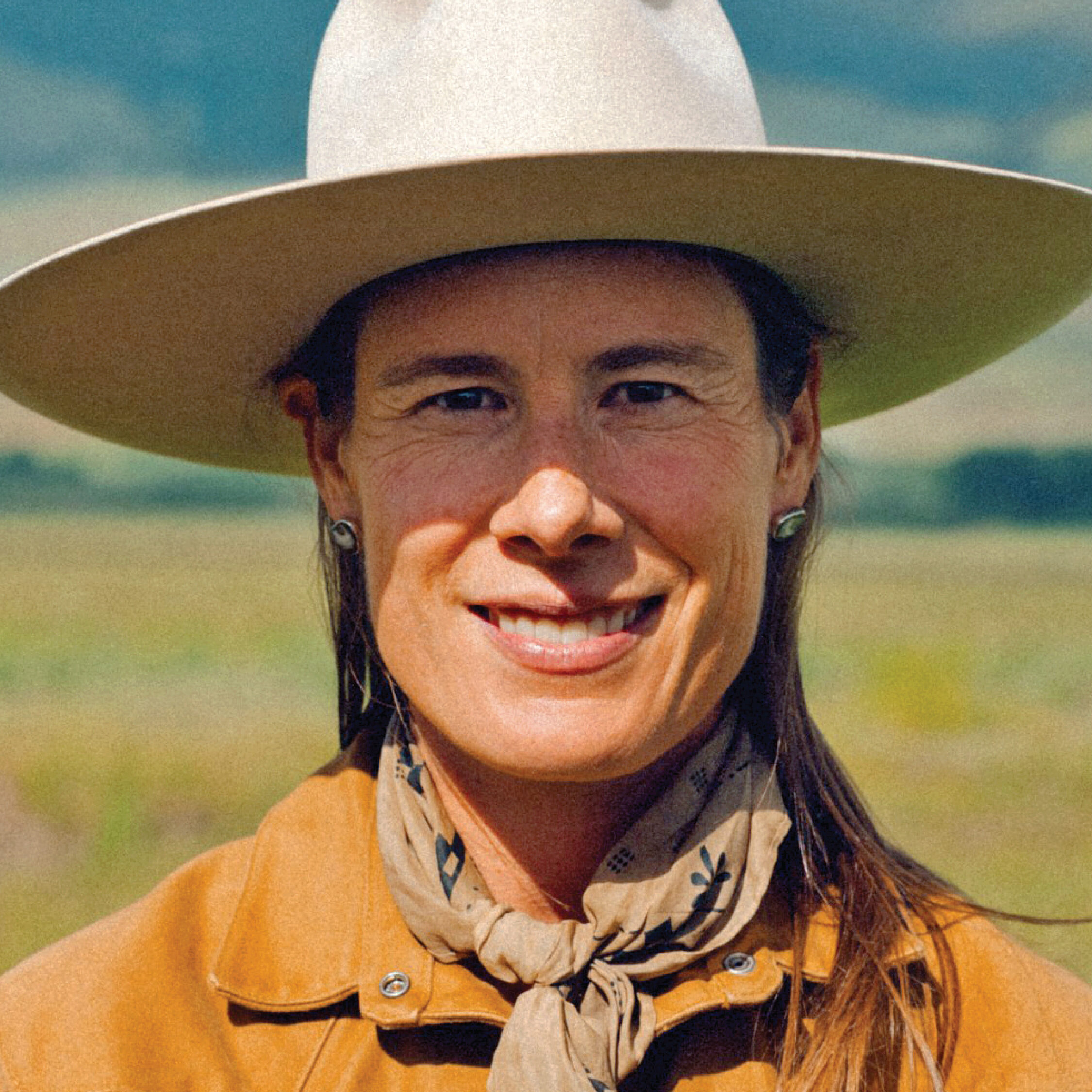 a woman in a Western-style hat look at the camera